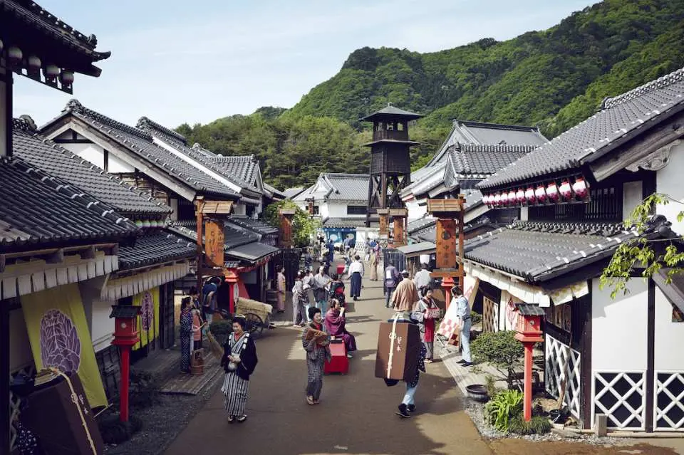 日光江戸村のにぎやかな街並み。江戸時代の伝統衣装を身につけた観光客が、趣のある建物の中を散策し、タイムスリップしたような日本文化を体験しています。