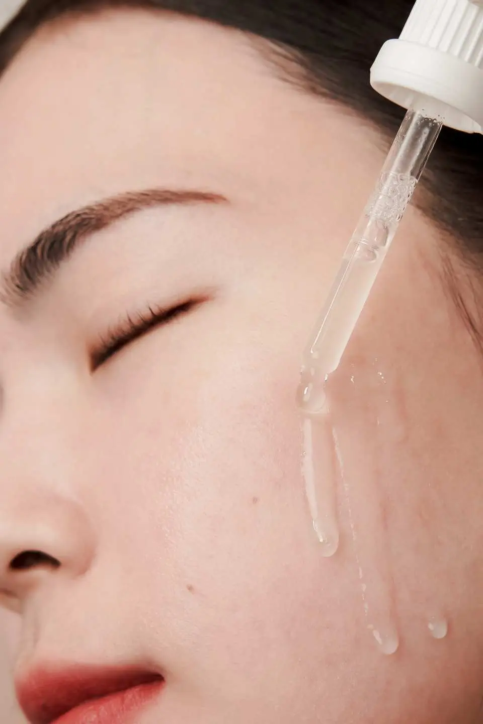 特写镜头显示顾客脸部肌肤，专业护理师轻柔地使用滴管涂抹精华液，体验十分美学减法保养，轻松养成灯泡肌。