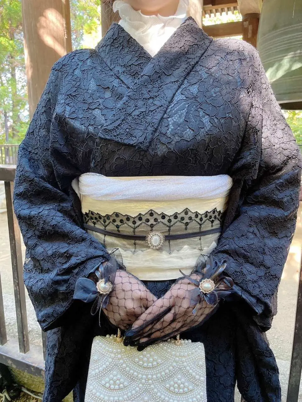 一件时尚黑色蕾丝和服的特写，搭配白色腰带、精致蕾丝手套和复古手提包，散发出现代优雅气息。