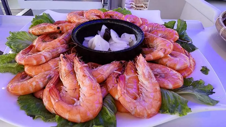 Close-up of a generous plate of fresh shrimp dish, with shrimp surrounding a special sauce, a delicious feast after watching the 'Baohuozai' fishing boats.
