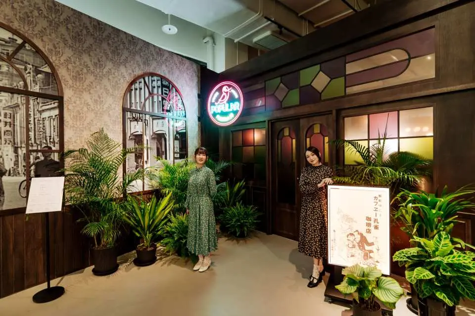 【孔雀珈琲店】1930 年代，咖啡店文化在臺灣蔚為風潮，融合精緻料理、酒精飲品與女給陪侍，成為現代感與浪漫情調交織的城市角落。女給陪聊解悶、提供情感慰藉，讓人們在香氣與燈影中暫忘煩憂。1932 年，茶商郭博容於大稻埕開設「孔雀珈琲店」，以華麗裝潢與 21 位女給打造摩登空間；隨後更創辦「博友樂唱片」，結合音樂與娛樂，引領臺灣流行音樂的早期發展。《摩登時代：唱片轉動・流行誕生》特展於臺北流行音樂中心文化館一樓復刻「孔雀珈琲店」，以珈琲店為圓心，融合博友樂的音樂元素，透過空間設計與復古細節，重現百年前珈琲文化樣貌。另外，持展覽入場憑證（含實體票根及電子票證）於孔雀珈琲店消費，憑展覽票券可享精緻小點乙份，
