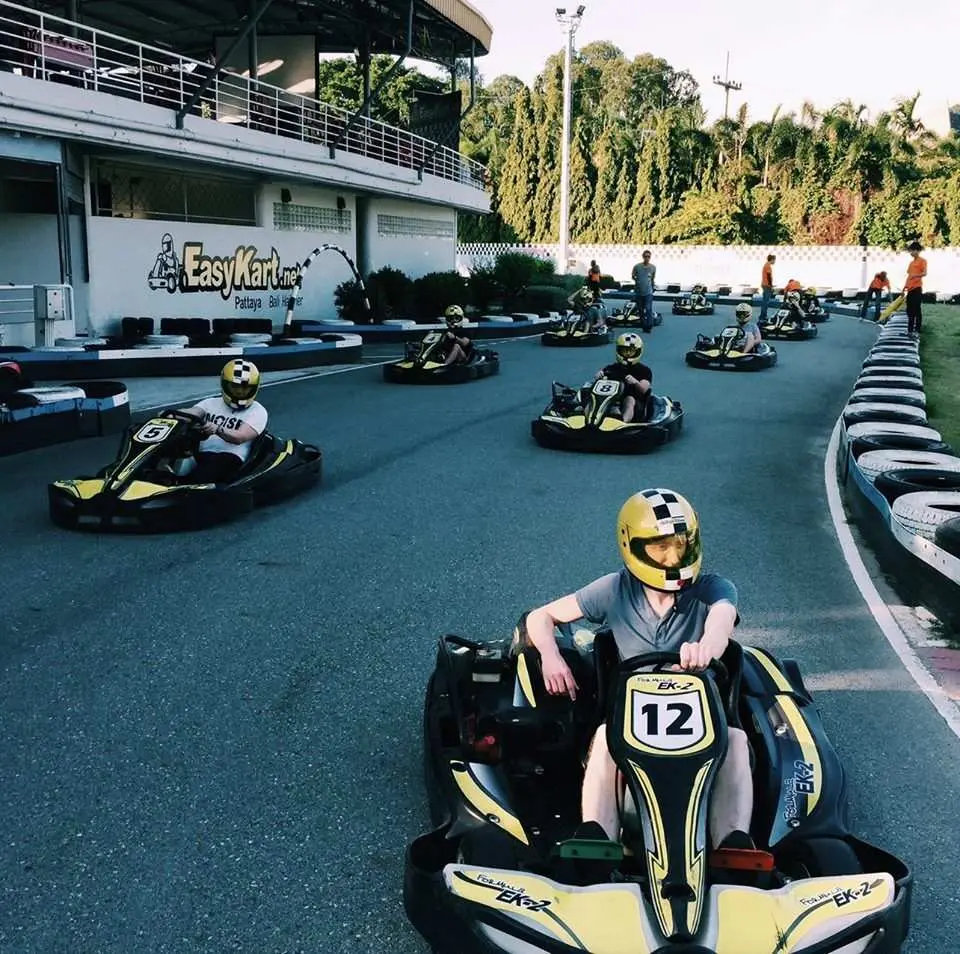 A driver at Pattaya’s EasyKart go-kart experience, wearing a yellow professional helmet, speeds kart number 12 on the spacious track, enjoying the fun and thrill of racing.