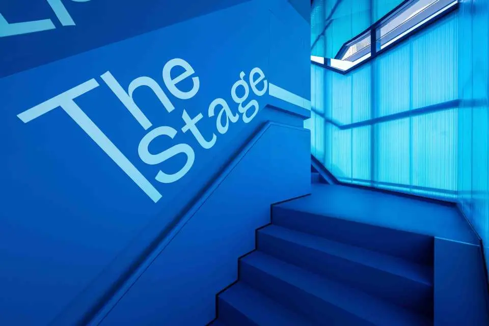 Bên trong Đài quan sát The Stage Thượng Hải, cầu thang và tường màu xanh hiện đại nổi bật với logo 'The Stage', dẫn dắt du khách khám phá không gian.