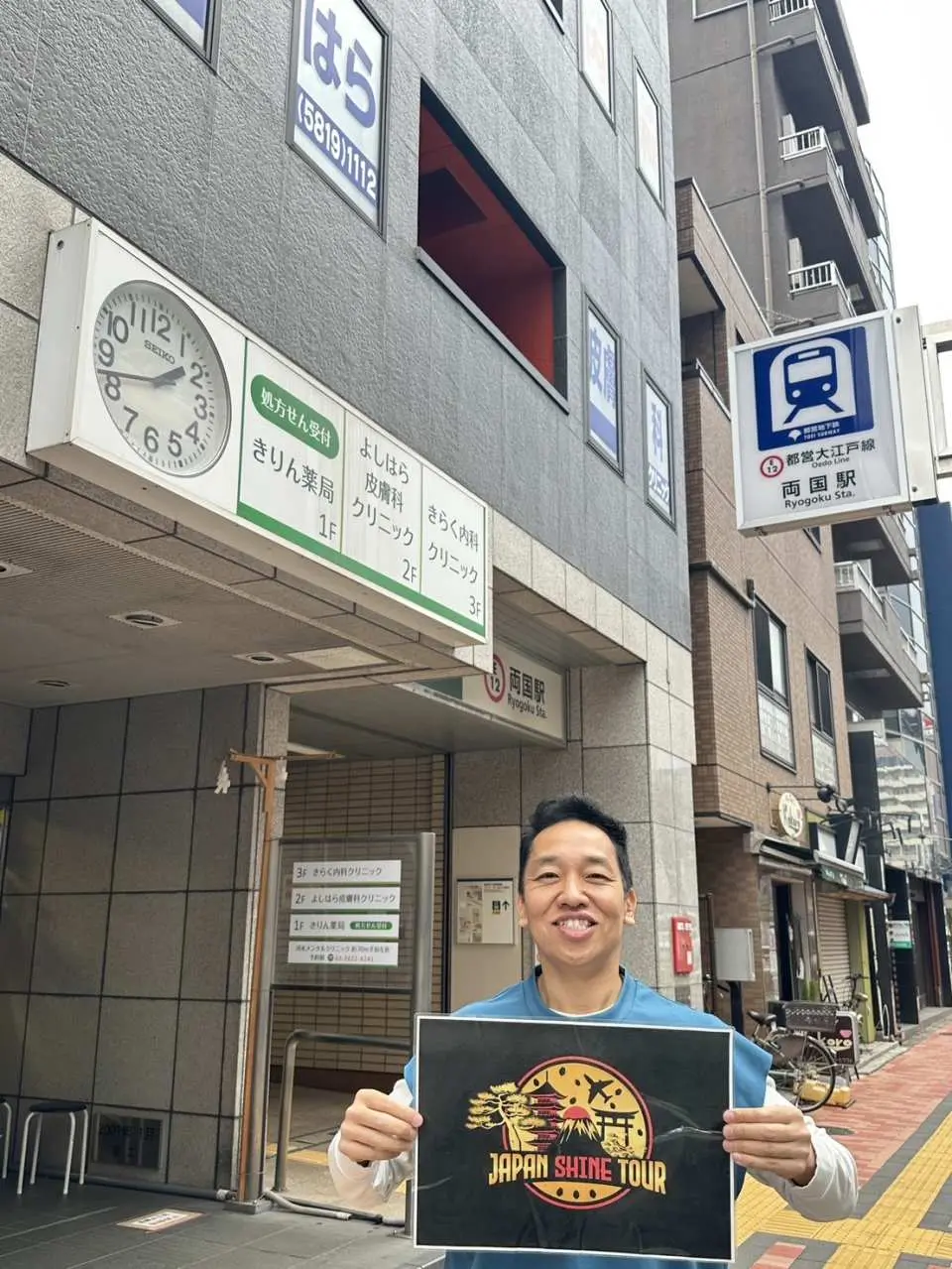 A professional tour guide holding a 'Japan Shine Tour' sign, welcoming visitors on a Tokyo street, ready to embark on a sumo cultural exploration.