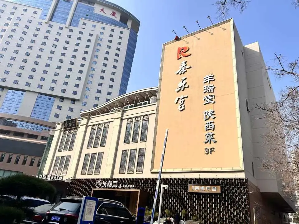 베이징 진러궁 서커스 공연장 외관으로, 전통 중국 건축 요소와 간판이 특징인 독특한 다층 건물이며 방문객을 맞이합니다.