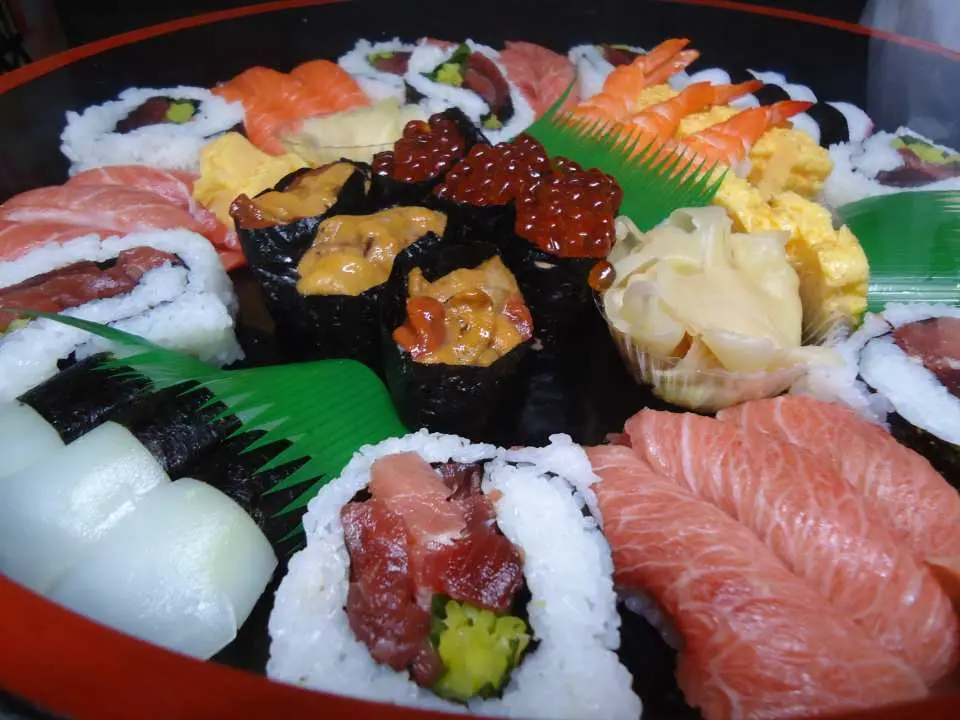 擺滿多種新鮮壽司和生魚片的大拼盤，有鮪魚、鮭魚、蝦和花壽司，展現屋形船餐點的豐富選擇。