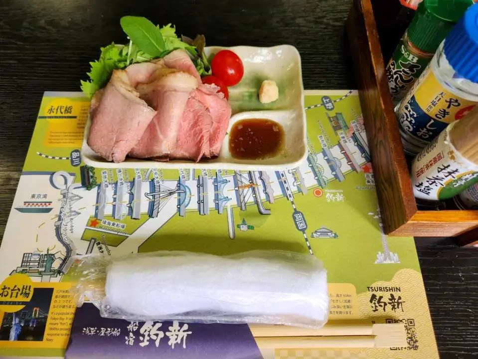 精緻的日式烤豬肉片，搭配新鮮生菜和特製醬料，口感軟嫩，是屋形船餐點中的一道美味佳餚。