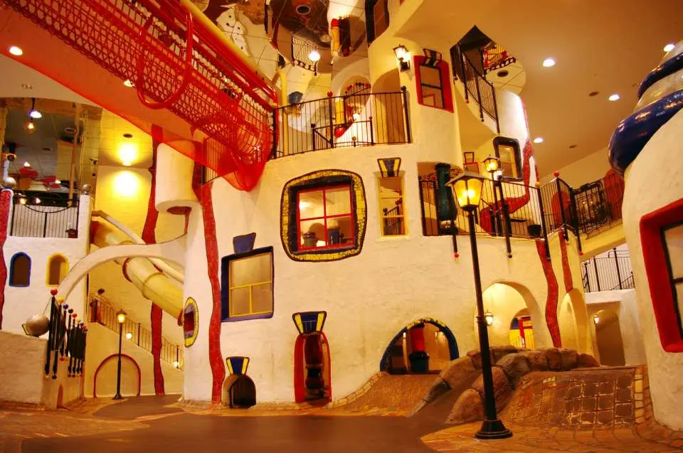 大阪儿童乐园KIDS PLAZA内部，展示着多层次的奇幻城堡或城镇建筑，设有窗户、阳台和滑梯，为孩子们提供丰富的探索空间。