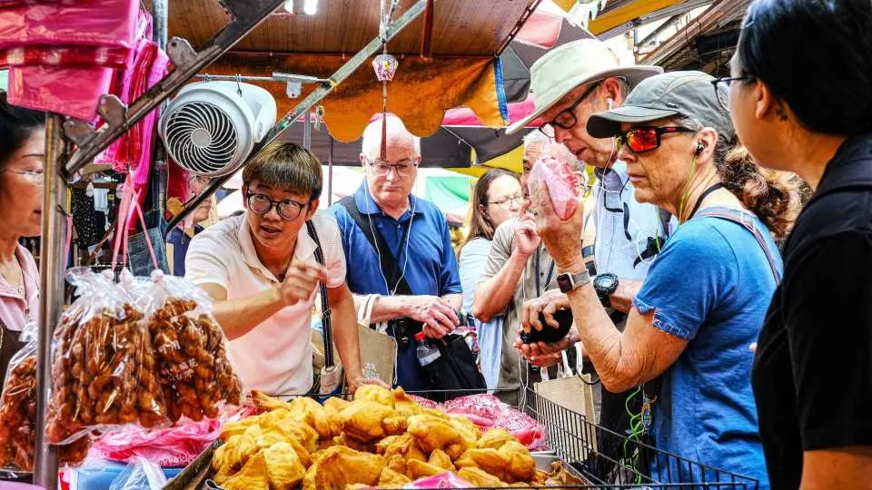 宜蘭傳統市場美食導覽，遊客熱情投入職人世界，仔細挑選並品嚐琳瑯滿目的傳統市場美味。