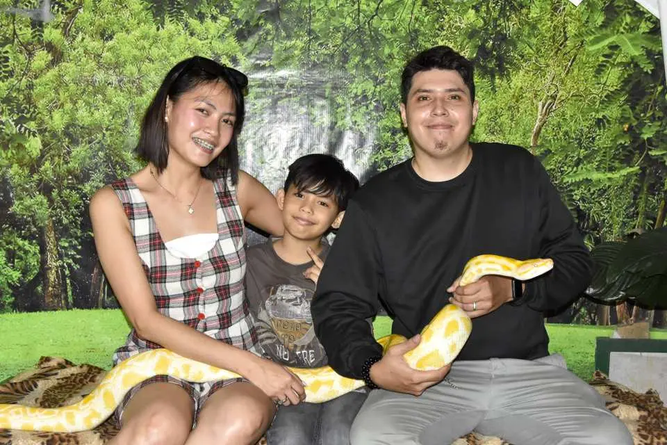 A family posing happily with a friendly yellow python at Zoori Zoo in Tagaytay, Philippines, creating unique and memorable animal interaction experiences together.