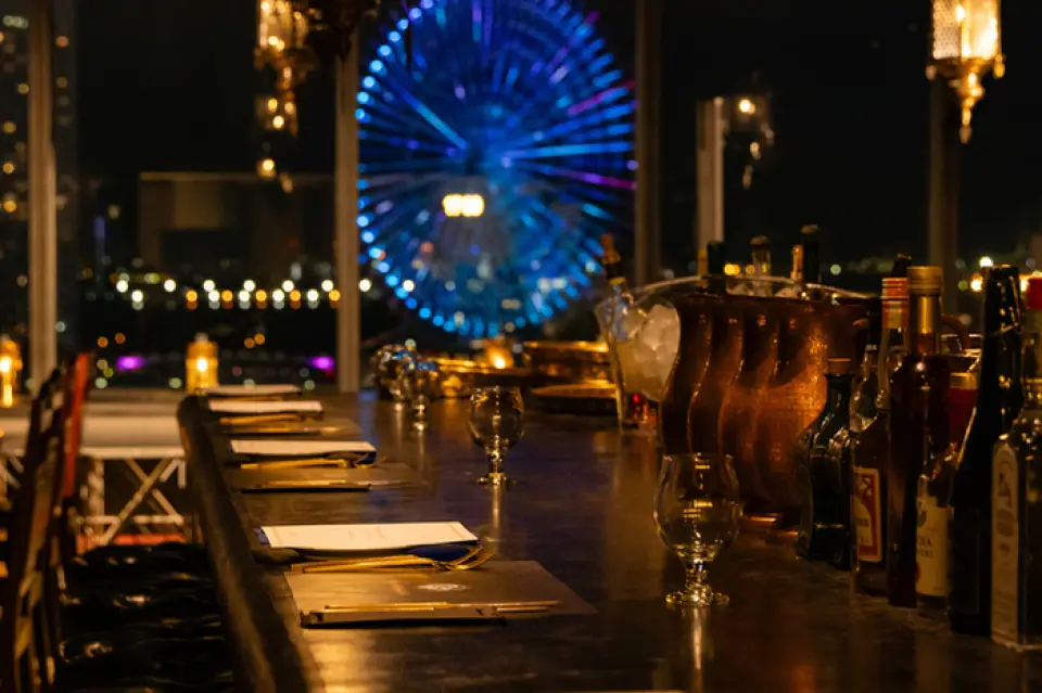 ร้านของเราตั้งอยู่บนชั้น 7 ของอาคาร Colette Mare ซึ่งเชื่อมต่อโดยตรงกับสถานี Sakuragicho ด้านหน้าอาคารสไตล์วิหารกรีกโบราณ โคมไฟแขวนสไตล์ตุรกีออตโตมัน โคมไฟติดผนังสไตล์พระราชวังอียิปต์ และพื้นไม้สักแอฟริกัน ล้วนตกแต่งพื้นที่ สร้างสรรค์บรรยากาศที่แปลกใหม่และพิเศษสุด เพลิดเพลินกับช่วงเวลาที่น่าจดจำพร้อมดื่มด่ำกับทัศนียภาพยามค่ำคืนอันงดงามที่สะท้อนผ่านหน้าต่างกว้าง 12 เมตร สูง 3 เมตร