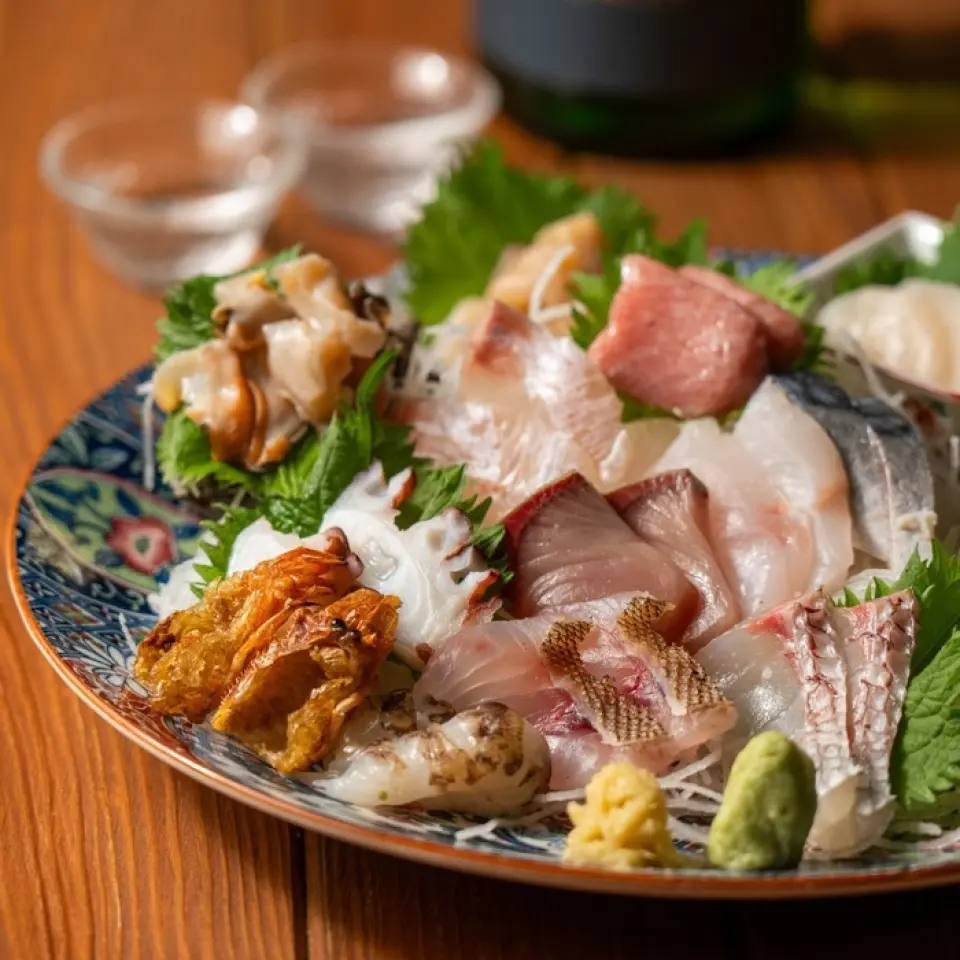 夜八行场的招牌菜是“生鱼本木盛”，这是一盘用各种调味料调味的拼盘。菜品阵容每天都会根据当天的捕捞量而变化。请尽情享用我们引以为豪的新鲜鱼肉！