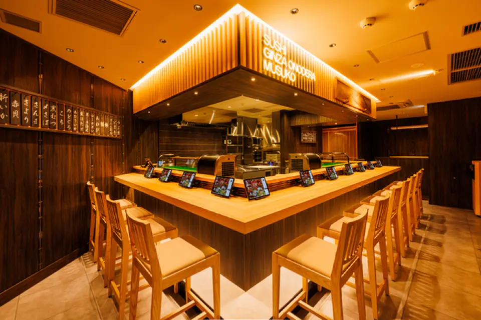 本店採用時尚現代的日式風格裝潢，樸素的木質吧台與黑色牆面形成鮮明對比，美不勝收。 LED霓虹燈閃耀在牆上，彷彿熱情地迎接顧客。店內設有15個吧台座位和2張四人座席，營造出輕鬆愜意的氛圍。吧台座位是可以近距離欣賞廚師精湛技藝的特別座位。請在時尚的空間裡，享受品嚐美食和美酒的幸福時光。