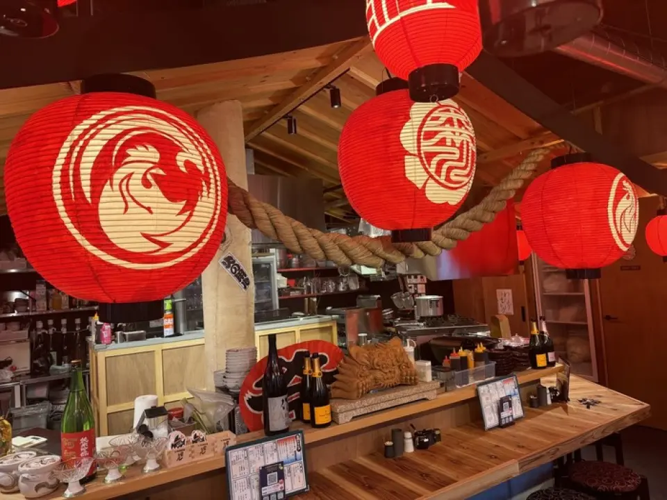 本店黑色的外墙和入口处的红灯笼格外醒目。一进门，仿佛置身于节日般的热闹氛围中！木质墙壁和水泥地面营造出如同神社般的传统空间。吧台座位面向厨房，您可以一边欣赏着与自己一起用餐的顾客的表情，一边享用美食。店内也提供充足的桌椅，可容纳4人至最多8人用餐！