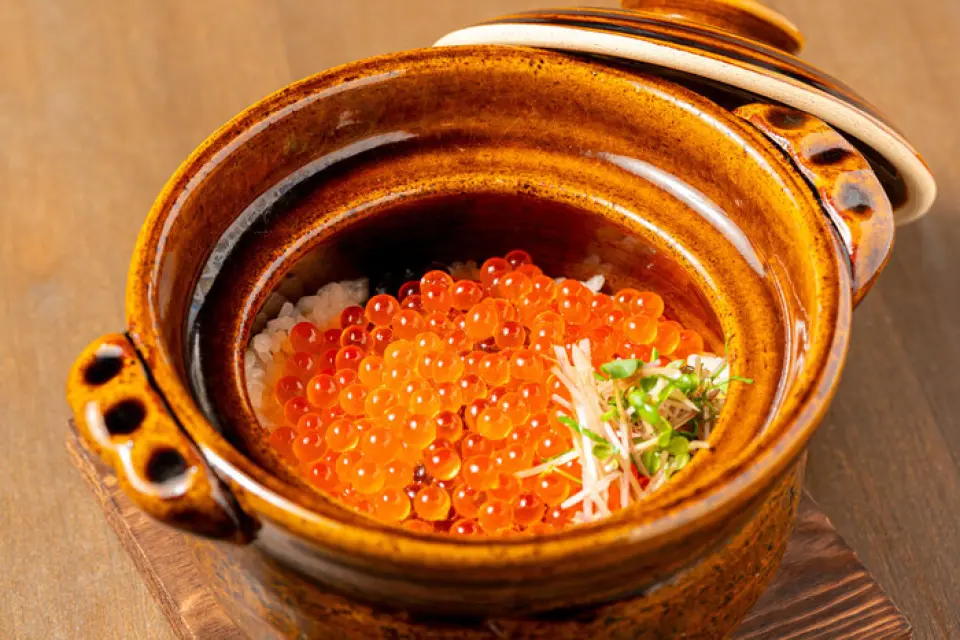 釜饭采用从米店采购的独家配方大米，搭配每天早晨新鲜熬制的高汤烹制而成。鸡骨和海带熬制的高汤浸透到米饭中，入口即化，美味无比！人气商品“鲑鱼籽釜饭”是一道奢华的菜肴，高汤与炭烤鲑鱼的鲜美融合，淋上足量的鲑鱼籽。