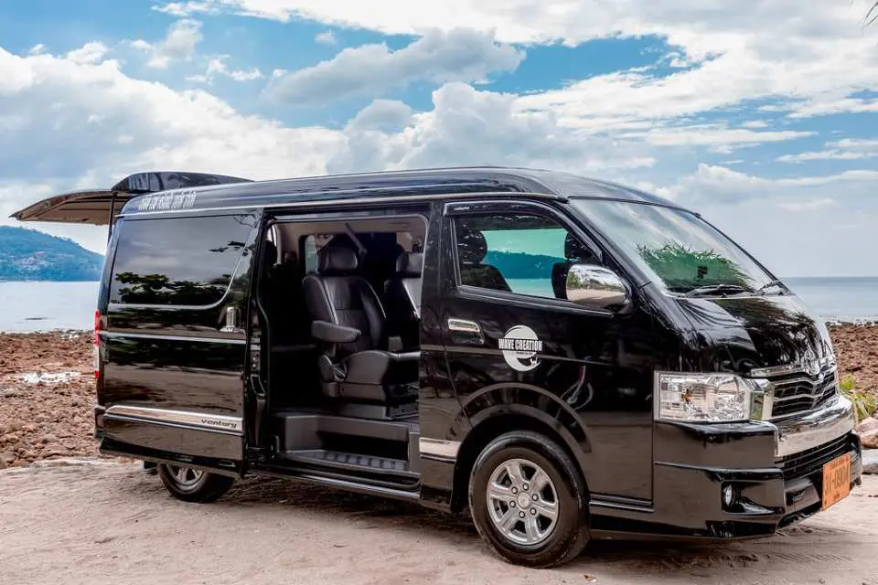 プーケットの海辺に駐車された黒いプレミアムバンで、ドアが開いており、空港送迎や島の観光に快適で安全な移動を提供します。
