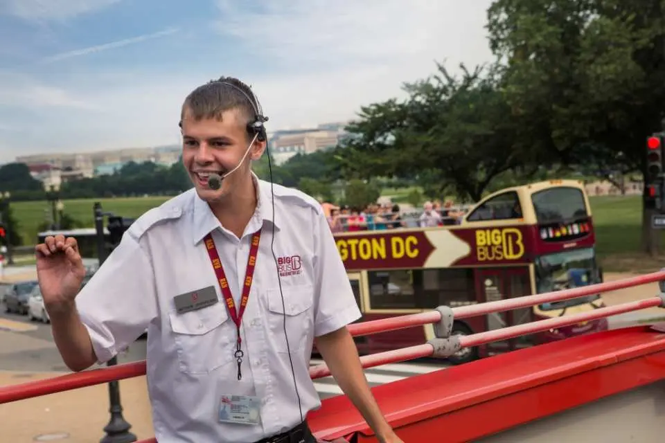 A cheerful, professional English-speaking guide from the Washington D.C. Big Bus tour welcomes passengers, ready to provide insightful commentary and local travel information.