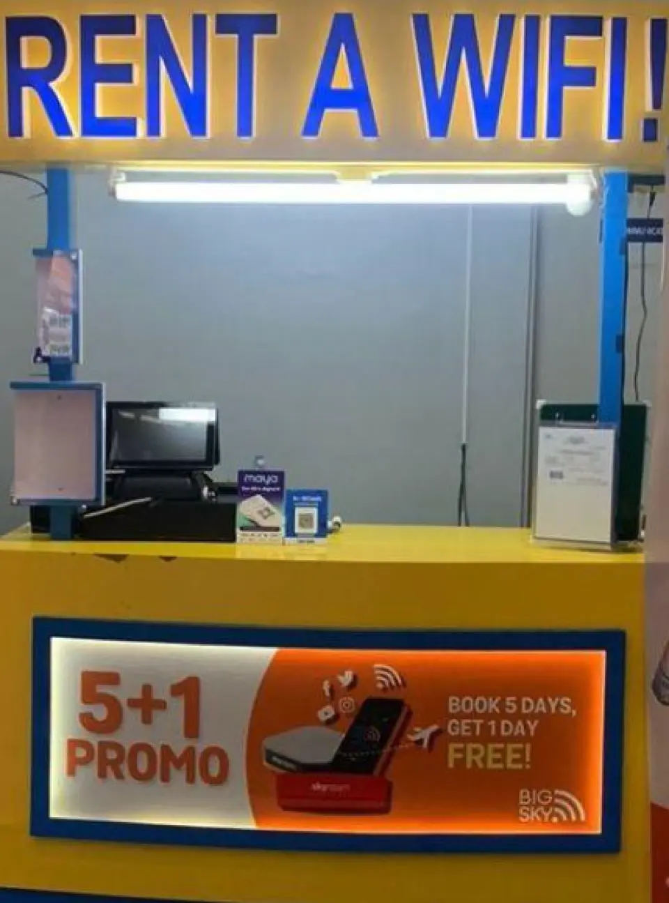 A bright yellow 'RENT A WIFI!' counter at Manila airport promoting a 5+1 day rental offer for convenient 4G LTE portable Wi-Fi device pickup.