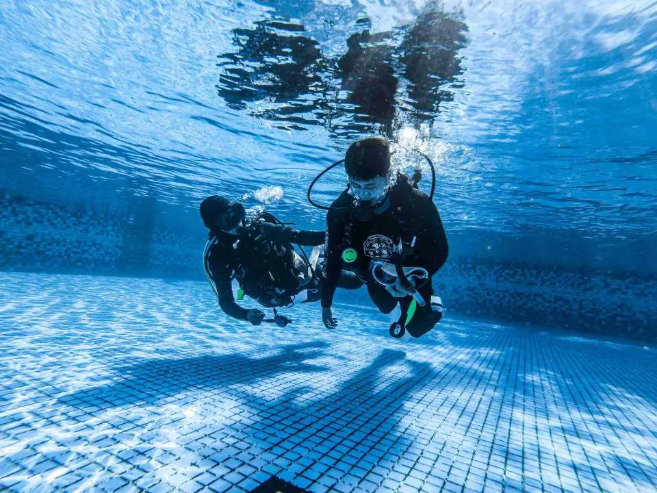 墾丁PADI潛水課程學員在泳池中練習水下安全技巧，教練一對一指導，掌握緊急應變能力。