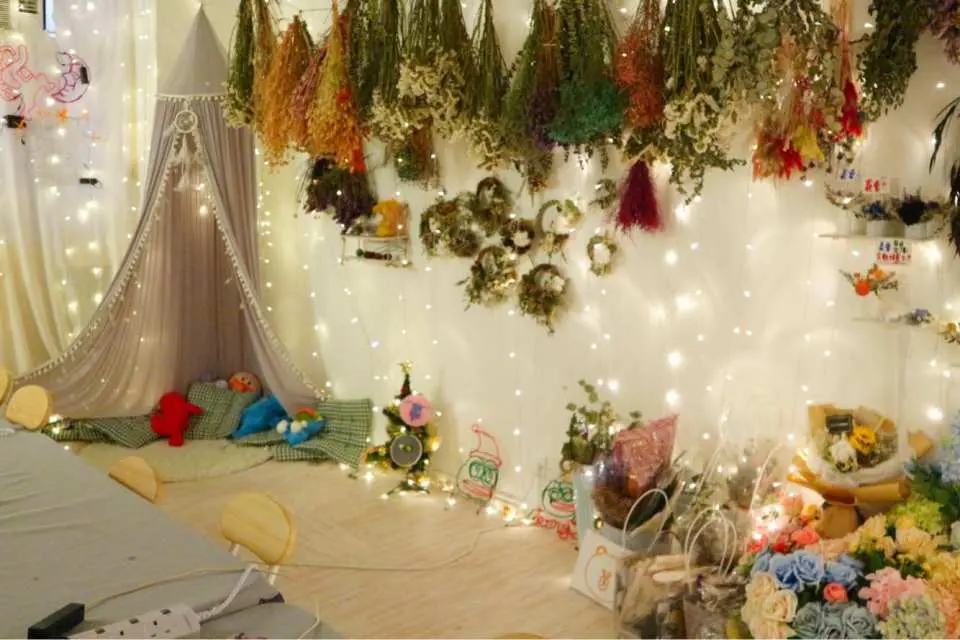A charming corner of Myosotis.flower Kwun Tong preserved flower studio, adorned with twinkling lights and hanging dried flower bouquets, creating a warm and romantic DIY workshop ambiance.