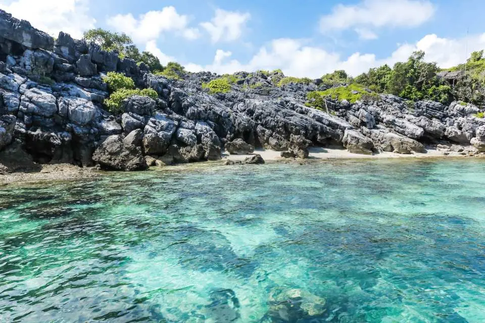 安通國家公園清澈見底的翡翠海水，礁石海岸線旁可見水下生物，提供蘇梅島浮潛探索豐富海洋生態的絕佳景點。