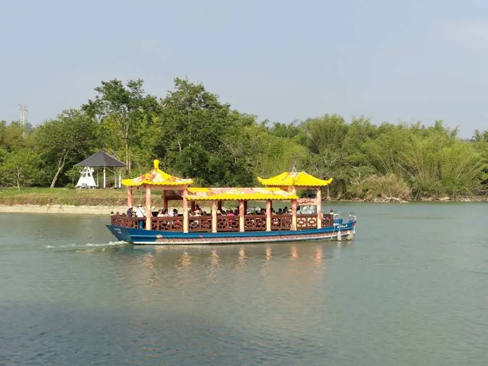 Tourists ride a vintage-style tour boat, slowly cruising on Wusanto Reservoir, admiring the lush greenery along the banks and enjoying the leisurely Siraya experience.