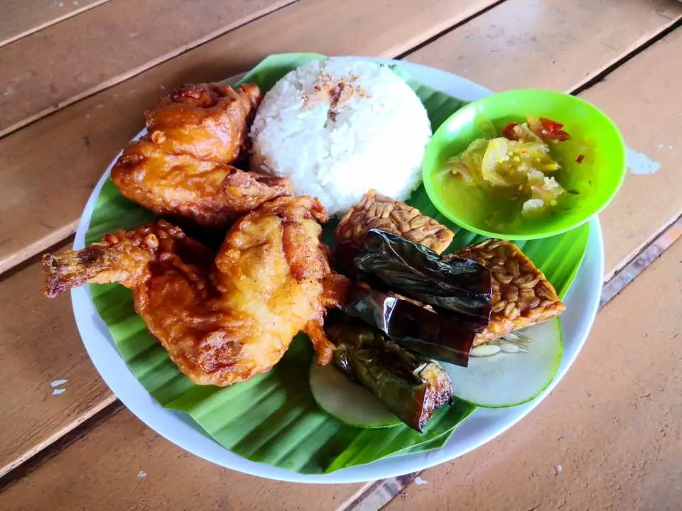 沙巴亞庇特色午餐，盤中盛放著炸雞、米飯、天貝及蔬菜，以香蕉葉墊底，呈現道地馬來西亞風味。