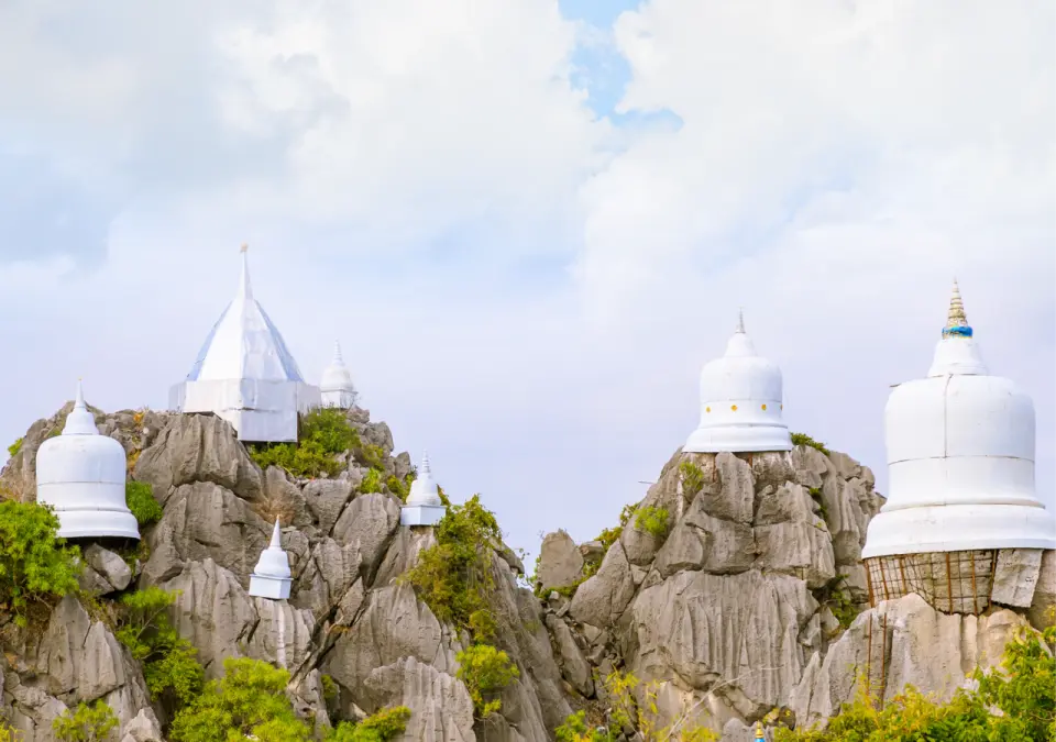 Majestic pagoda peaks in Lampang, Thailand, featuring multiple white stupas perched atop rugged limestone hills, showcasing a unique blend of religious and natural scenery.