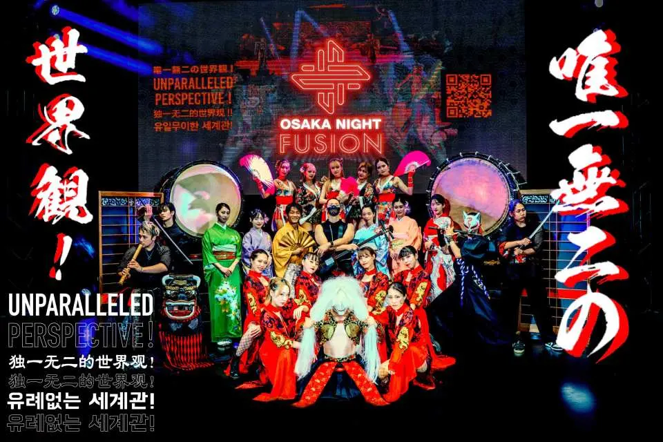 大阪之夜融合表演的演员大合照，展示多元化的日本太鼓、歌舞伎与武士舞蹈服装，背景是闪烁的演出标题。
