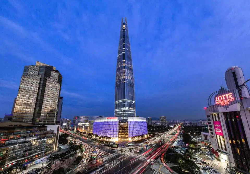 首尔乐天世界塔与乐天世界购物中心夜景，车流灯光璀璨，城市标志性建筑尽显繁华，体验首尔天空购物。