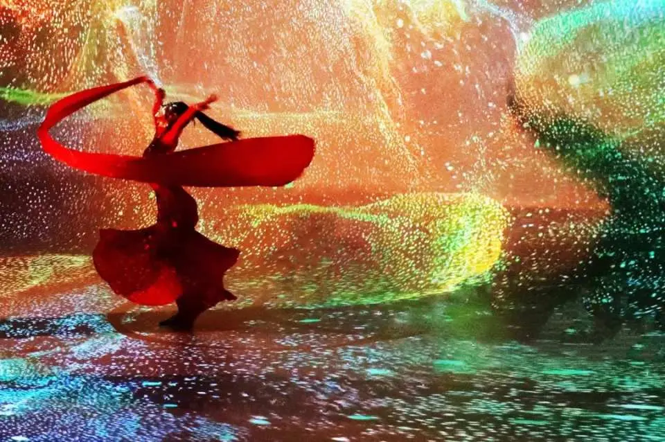 A dancer in a red gown performs amidst a stunning immersive digital light and shadow art projection at Beijing Palace Banquet's gallery, creating a visually spectacular experience.