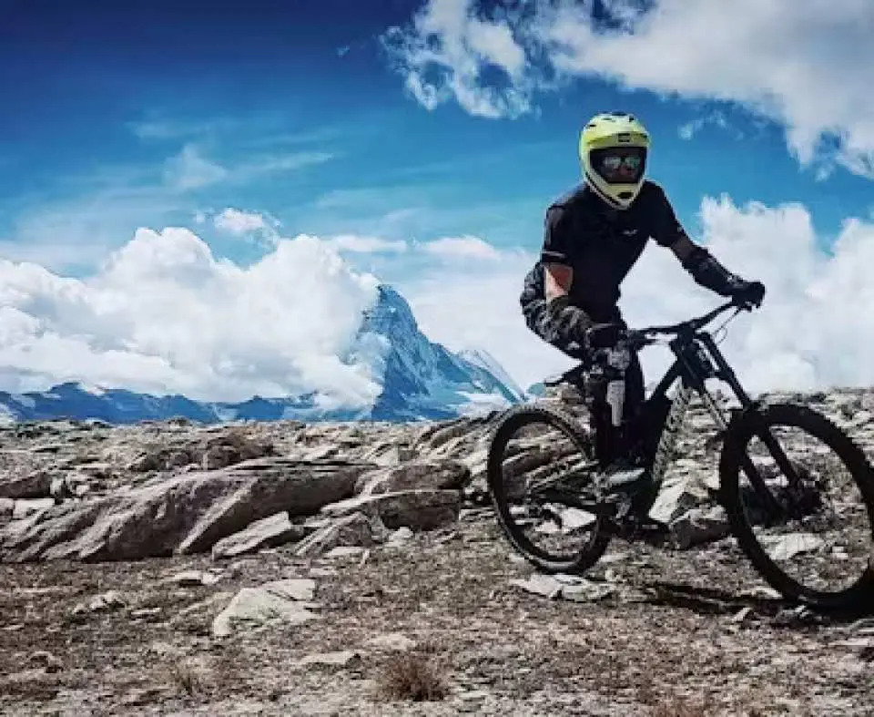 在私人導遊的帶領下，一名騎行者沿著策馬特的山路騎行，背景是阿爾卑斯山的全景和標誌性的馬特洪峰。