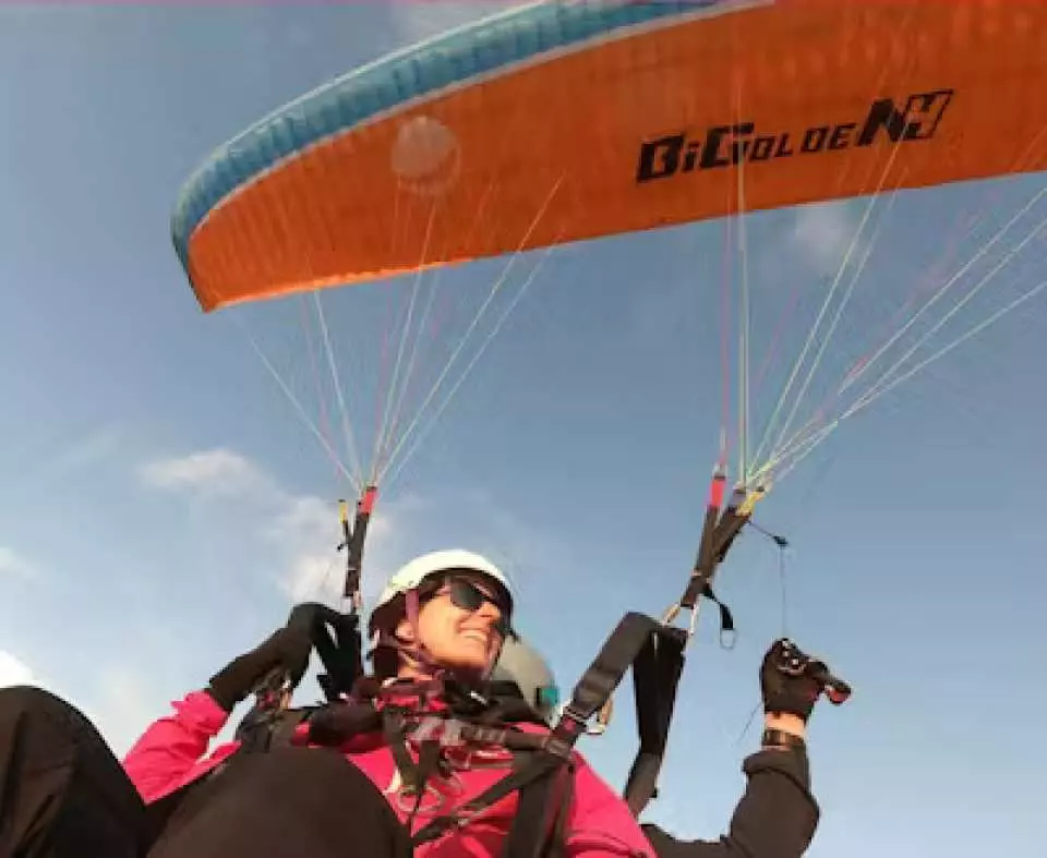 A passenger enjoying a private tandem paragliding flight in Davos, Switzerland, admiring the views from high above, showing an excited and joyful experience.