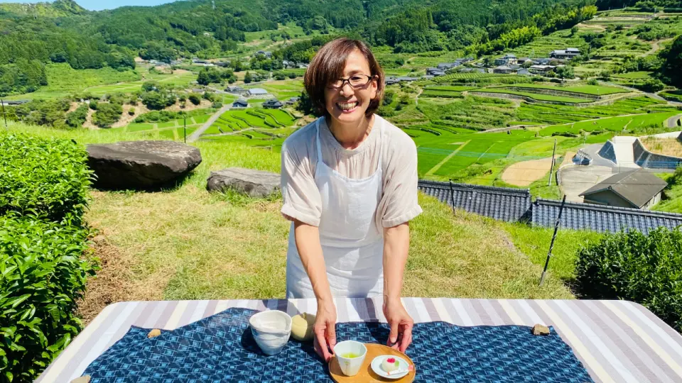 波佐見町茶農在梯田背景前，自豪地展示泡好的日本茶與甜點，期待與您共享。