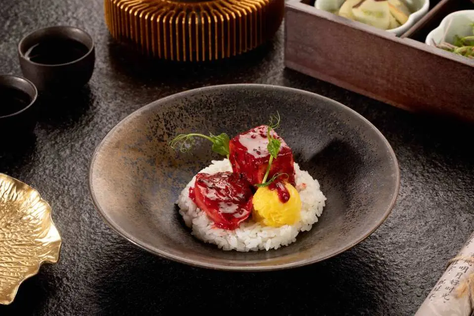 青島蘭齊宴賦精緻宮宴菜餚，一碗白米飯上佐以紅色方塊珍饈與金黃色醬料，展現中華美食與擺盤藝術的完美結合。