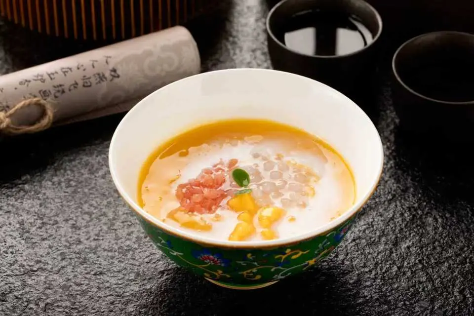 青島蘭齊宴賦的精緻宮廷甜點，繽紛湯品中點綴著晶瑩西米露與新鮮柚子肉，藝術擺盤與口感兼具，提升美食文化附加價值。