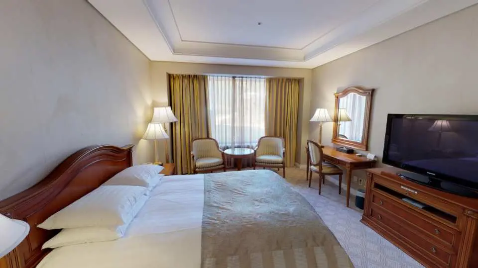 A luxurious guest room included in the High1 Ski Accommodation Package, featuring a comfortable king bed, elegant furniture, and a separate seating area for relaxing after skiing.