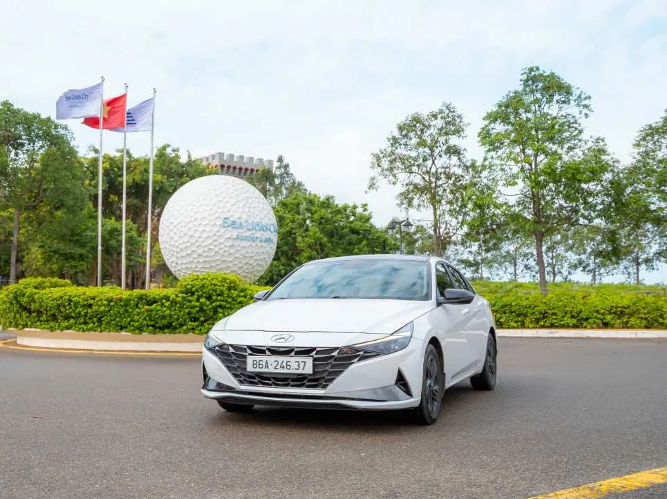 一輛白色現代房車停靠在度假村前，為芽莊至胡志明市的私人接送提供舒適的4人座交通選擇，適合個人或小家庭。