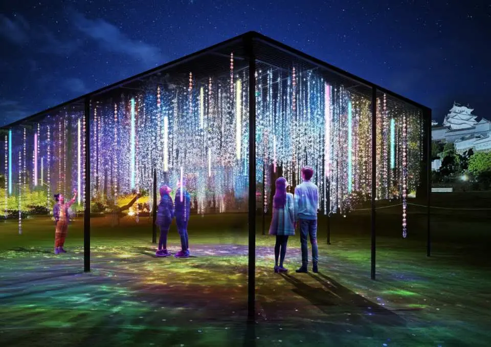 Himeji Castle "DANDELION PROJECT" interactive light art: Visitors immerse themselves in a dreamlike scene of colorful digital light rain, with the castle visible in the distance.