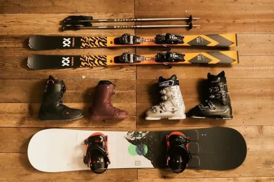 Overhead view of complete ski and snowboard rental equipment for Togakushi Ski Resort: skis, poles, various boots, and a snowboard.