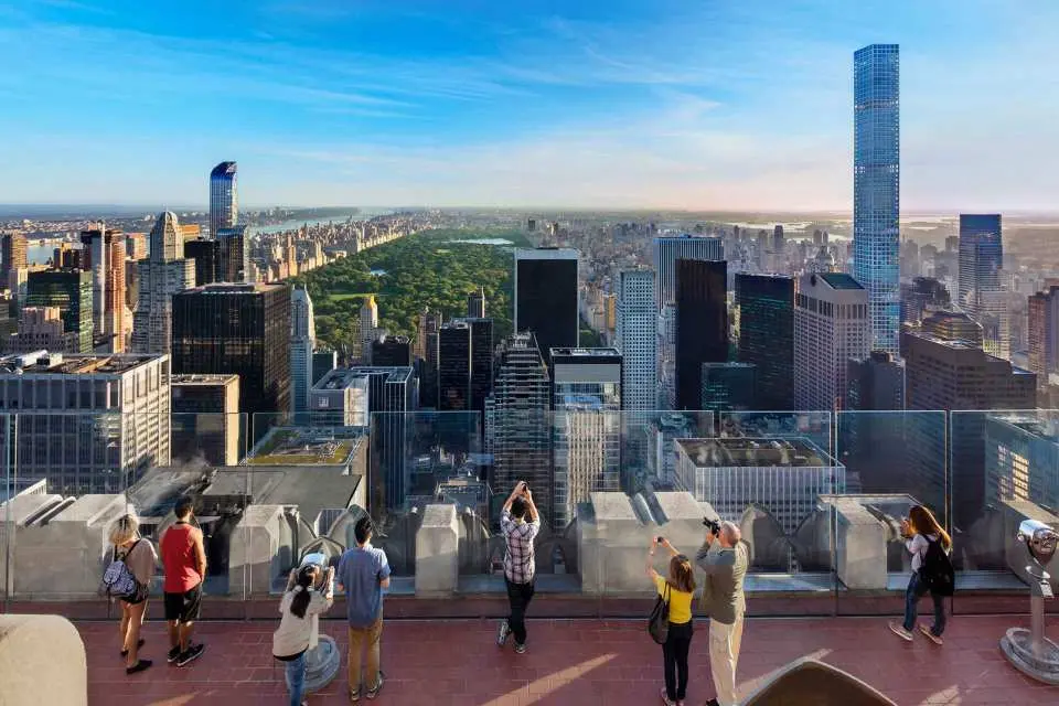 Visitors on a high-rise observation deck enjoying a spectacular panoramic view of Central Park and the sprawling New York City skyline.