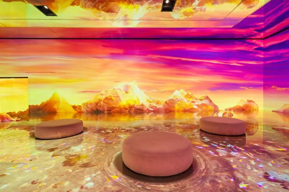 韓國仁川Le Space沉浸式媒體藝術展的「平行宇宙」區，一個空曠的空間中，壯麗的日落山脈和水面投影在牆壁和地板上。