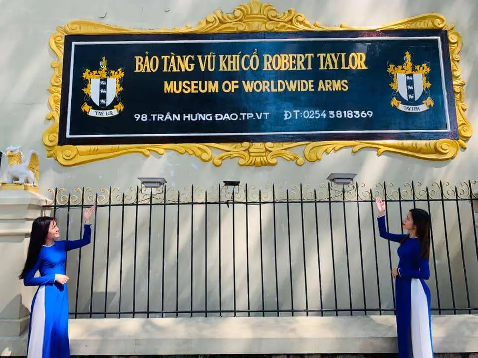 Entrance to the Robert Taylor Museum of Worldwide Arms in Vung Tau, featuring two women in traditional Vietnamese Ao Dai in front of the historic French villa exterior.