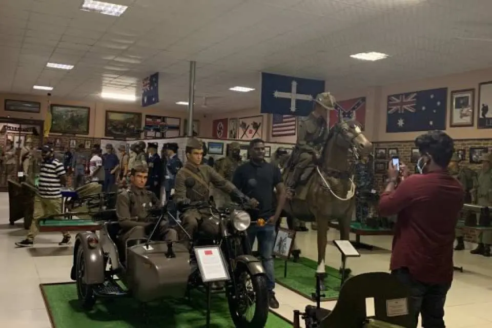Spacious exhibition hall at the Robert Taylor Museum of Worldwide Arms, featuring diverse military equipment, antique motorcycles, cavalry models, and visitors exploring.