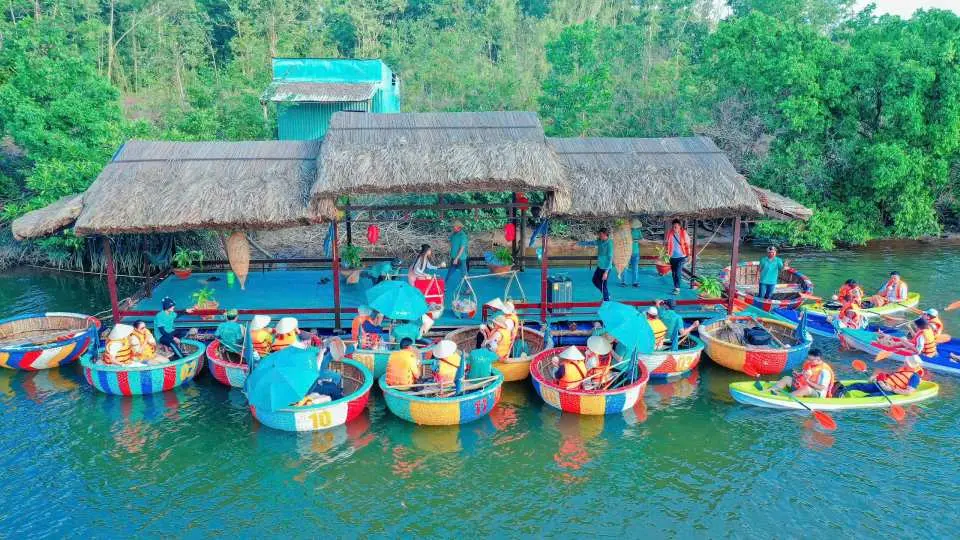 Phu Quoc basket boat fleet gathered at a floating rest stop, where tourists enjoy leisure time by the tranquil Cua Can River, experiencing the floating market atmosphere.