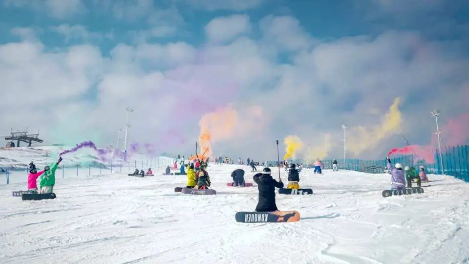 雲頂滑雪公園內，一群單板滑雪愛好者手持彩色煙霧棒，在雪地上展現活力與激情，享受冬奧會場地的樂趣。