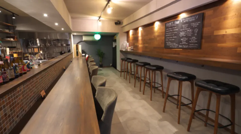 Nội thất cửa hàng được thiết kế đơn giản, thống nhất với vân gỗ và màu sắc trang nhã. Có hai loại chỗ ngồi để lựa chọn tùy theo dịp. Quầy chính được khuyến khích cho những ai muốn thưởng thức đồ ăn và đồ uống một cách thư thái. Quầy phụ, được trang bị ghế không tựa lưng, là nơi lý tưởng để nhâm nhi đồ uống nhanh theo kiểu bán đứng. Quán chỉ cách ga Hankyu Ashiyagawa 3 phút đi bộ, rất thuận tiện cho việc di chuyển. Nếu bạn muốn thưởng thức bia Bỉ hảo hạng, đừng ngần ngại ghé qua nhé.