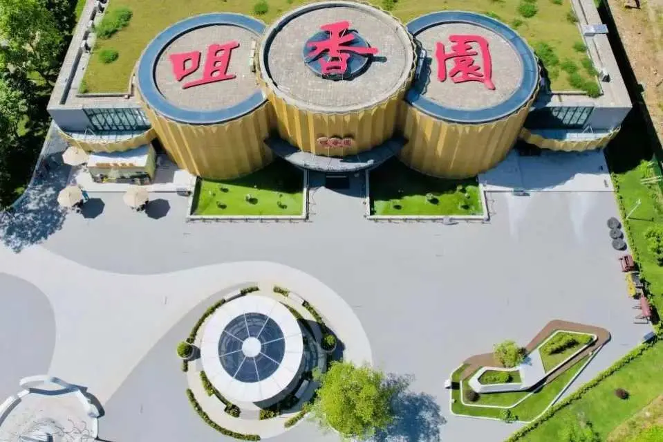 中山【咀香園餅文化博物館】鳥瞰圖，展示其獨特的圓筒形建築和周圍綠化景觀，是短線團參觀的文化景點。