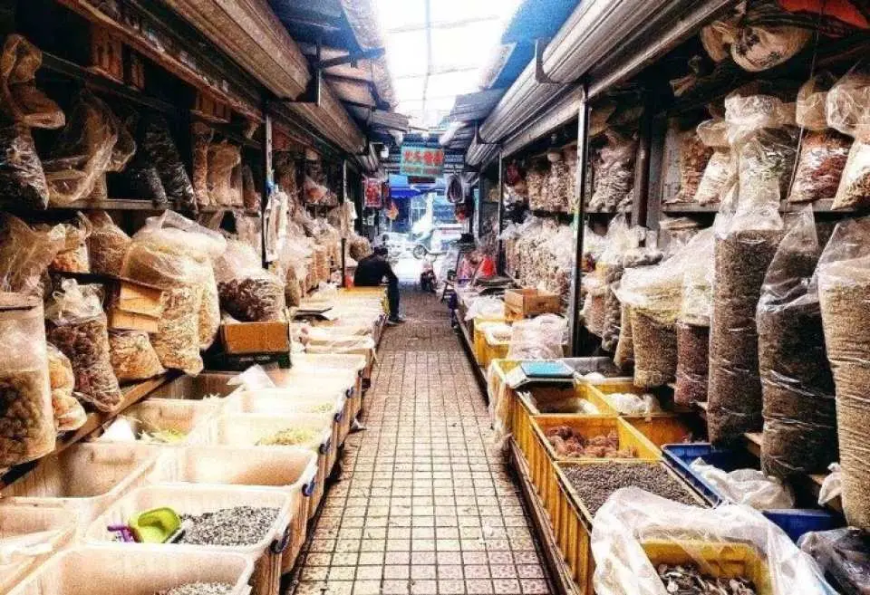 中山【沙崗墟】百年煙火市集巷道，兩旁小攤販擺滿各式商品，展現當地熱鬧的傳統市集氛圍，是團體旅遊的亮點。