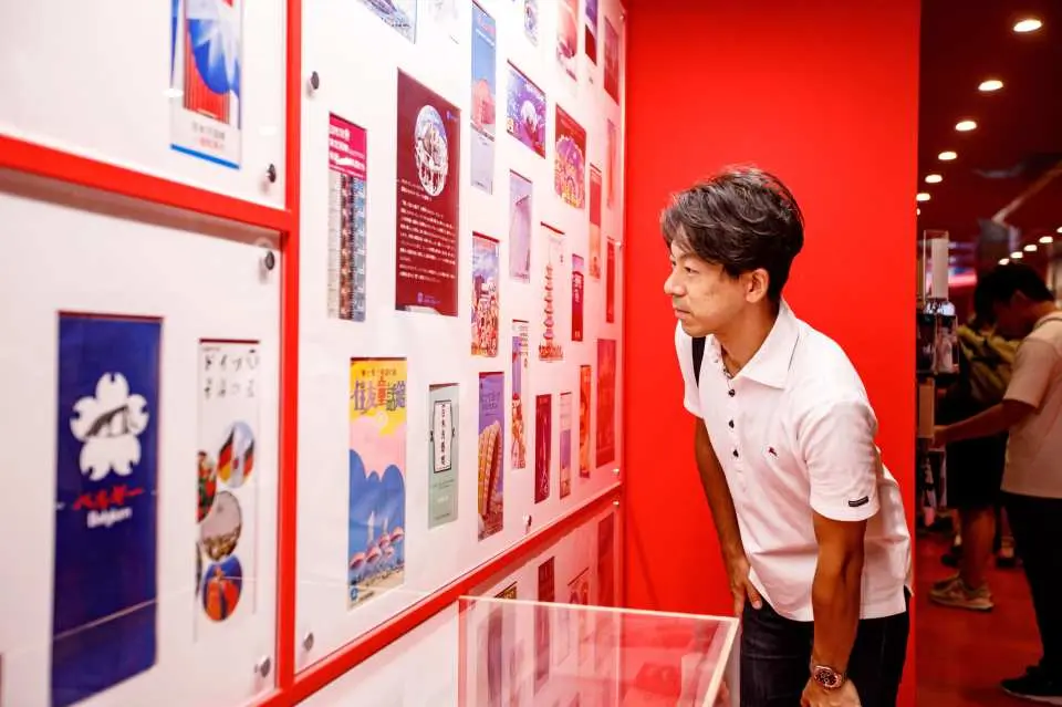 一位游客在万博纪念公园展馆内，凝神观赏墙上展示的1970年大阪万博珍贵历史海报，回顾日本经济奇迹年代。